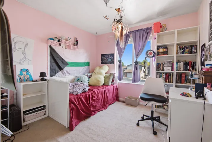 Carpeted room with a window, flanked by white built-in shelving and white freestanding shelving units