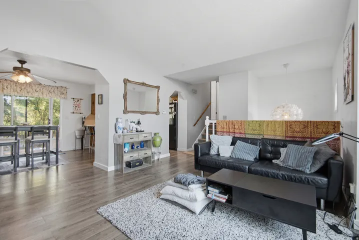Open-concept living area featuring wood-finish flooring, white walls, and a ceiling fan in the dining space