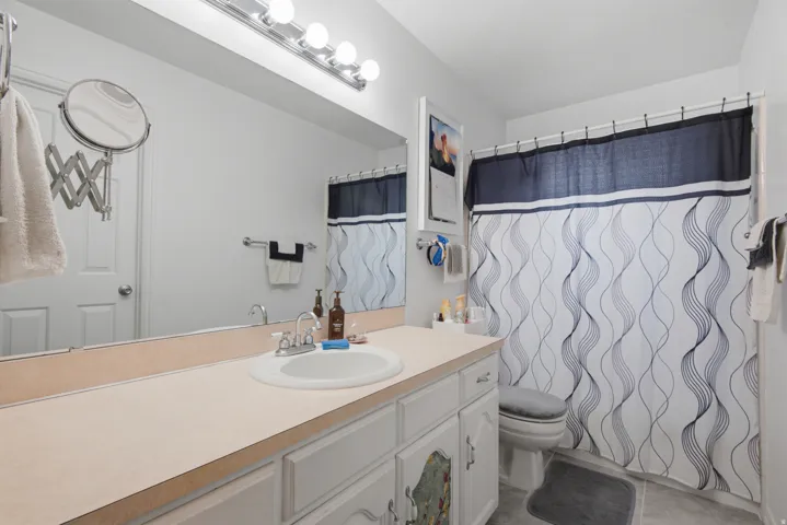 Bathroom featuring a vanity with an integrated sink, a large wall-mounted mirror, and overhead lighting