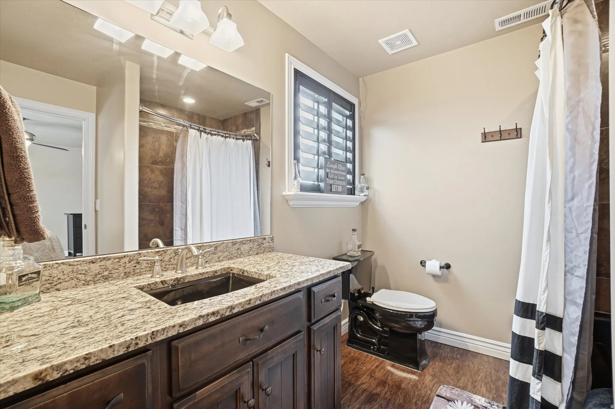 Bathroom featuring vanity, curtained shower, and dark wood-type flooring