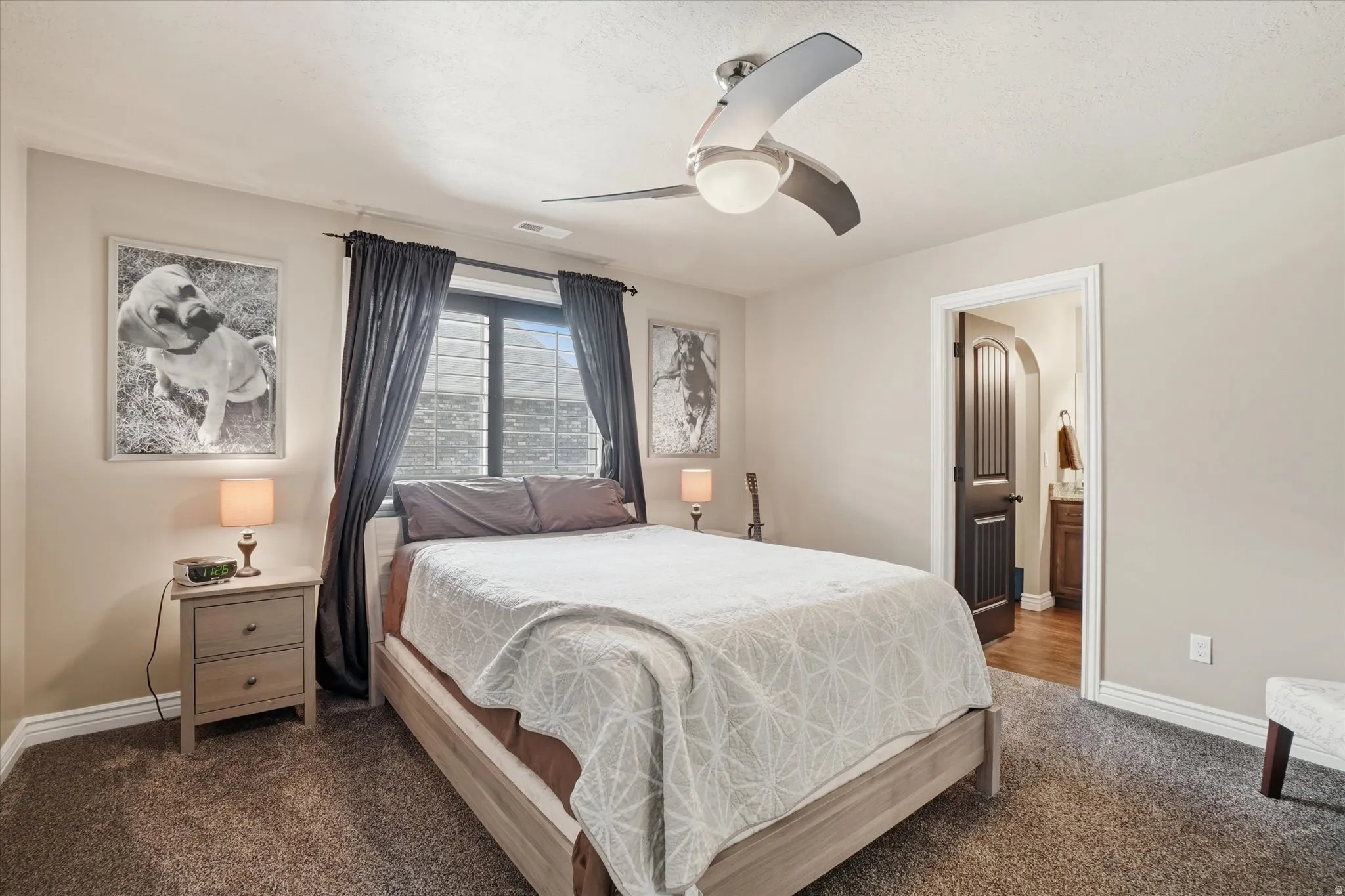 Bedroom featuring dark colored carpet, a ceiling fan, and connected bathroom