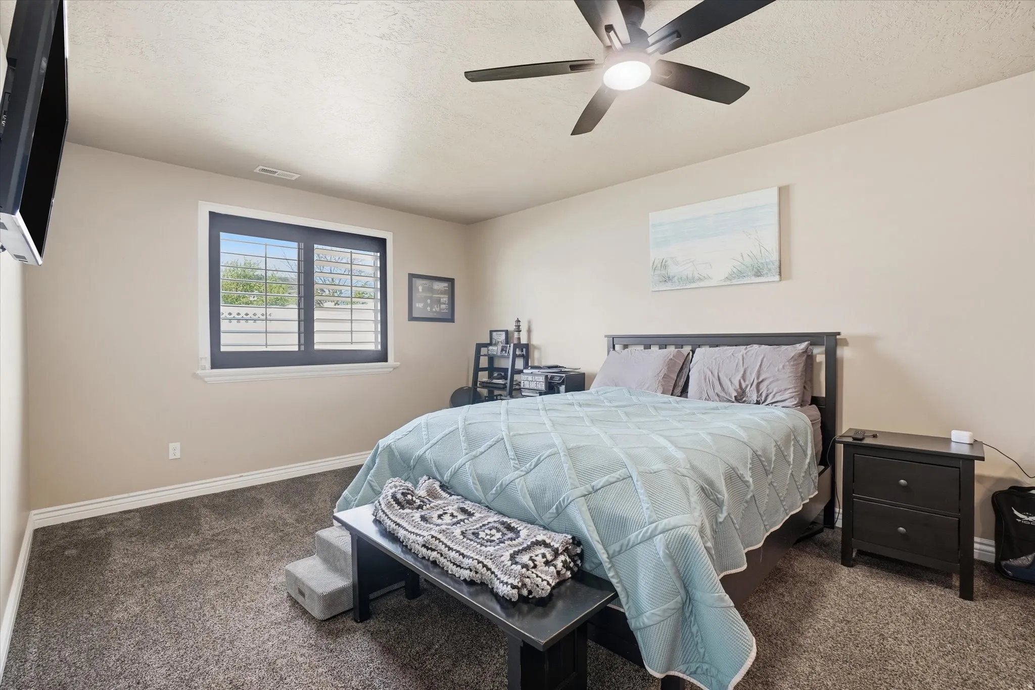 Bedroom with dark carpet, a ceiling fan, and a textured ceiling