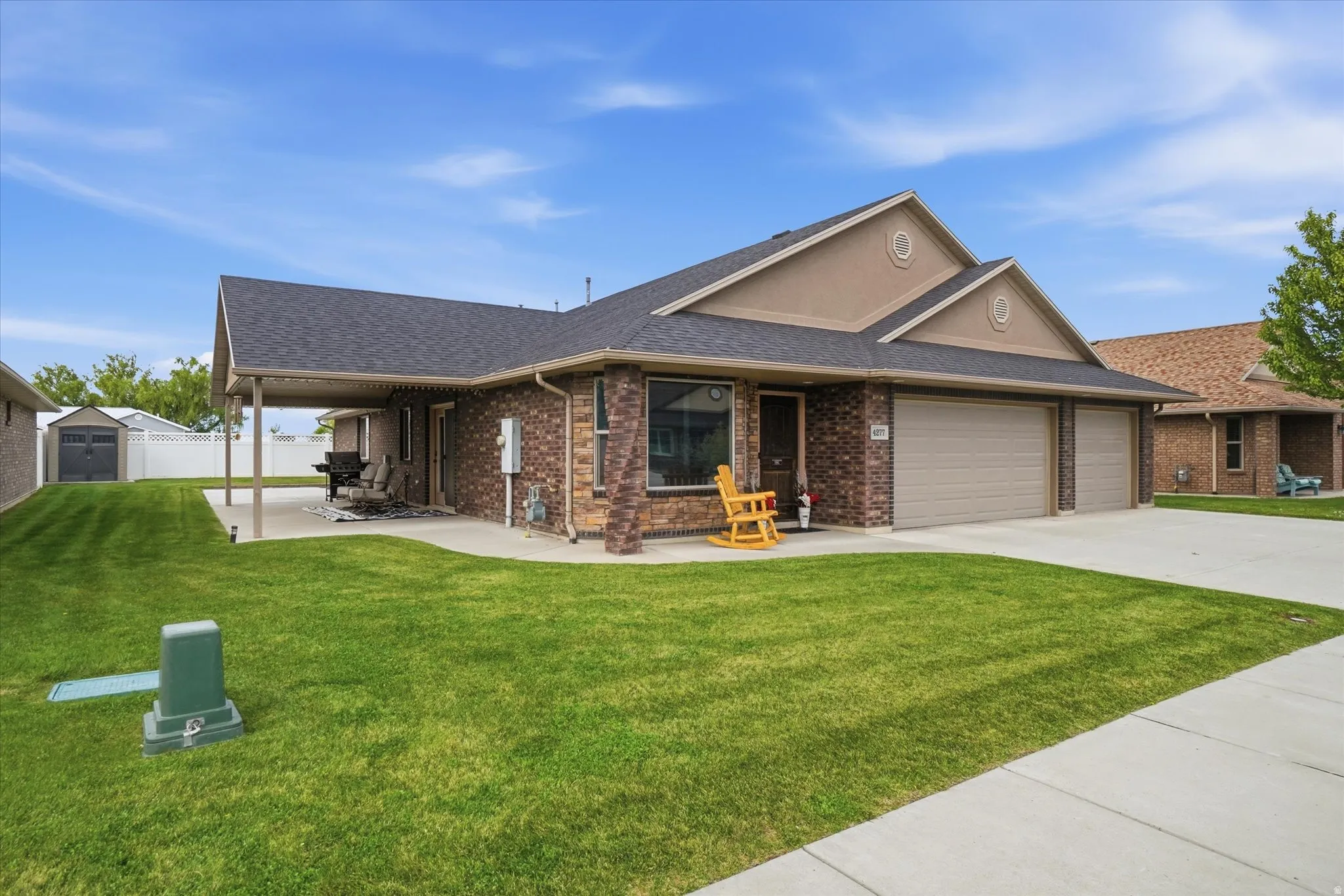 Ranch-style house with brick siding, a garage, a shingled roof, driveway, and a shed
