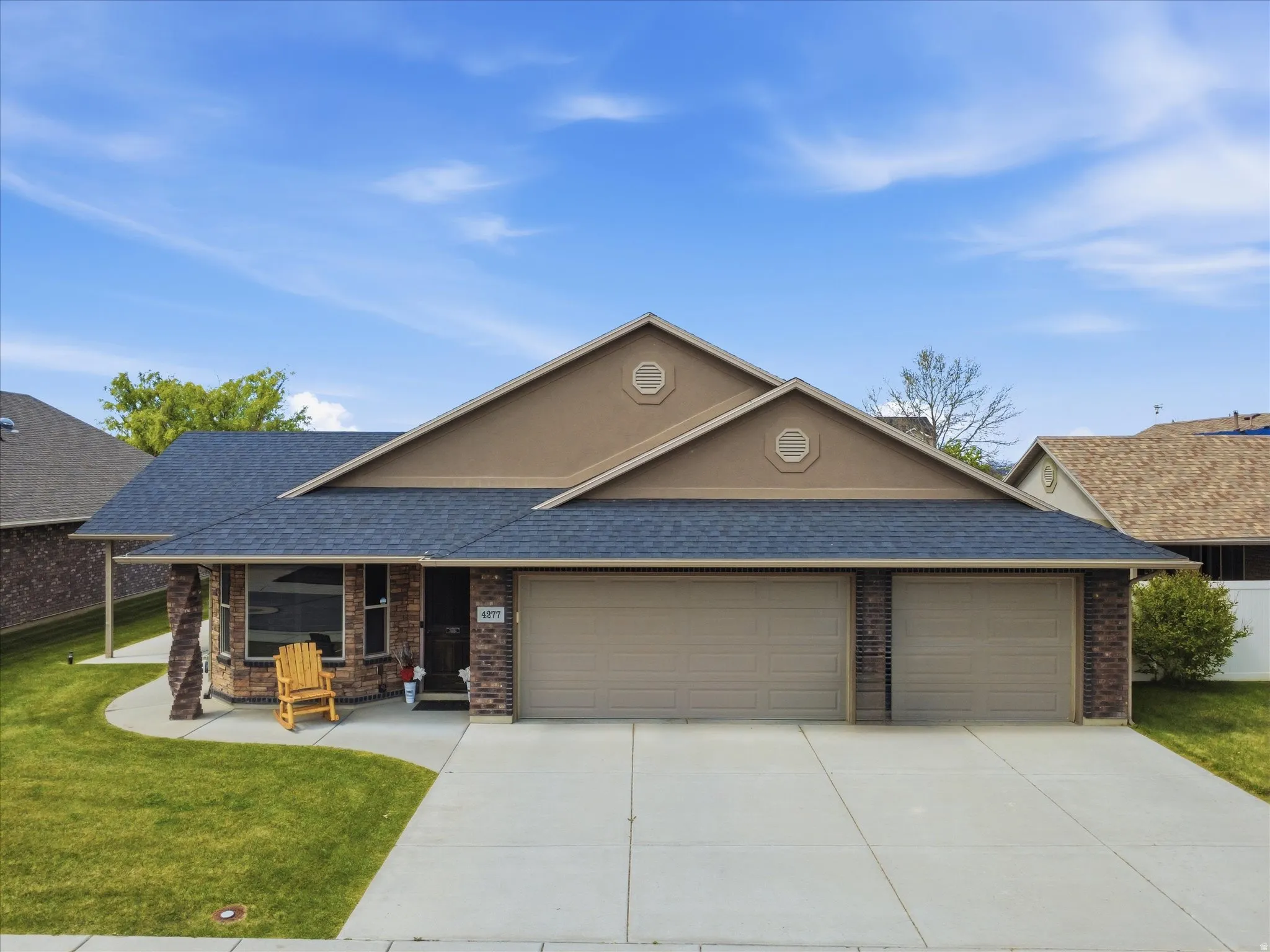 View of front of house with roof with shingles, an attached garage, a front lawn, driveway, and covered porch
