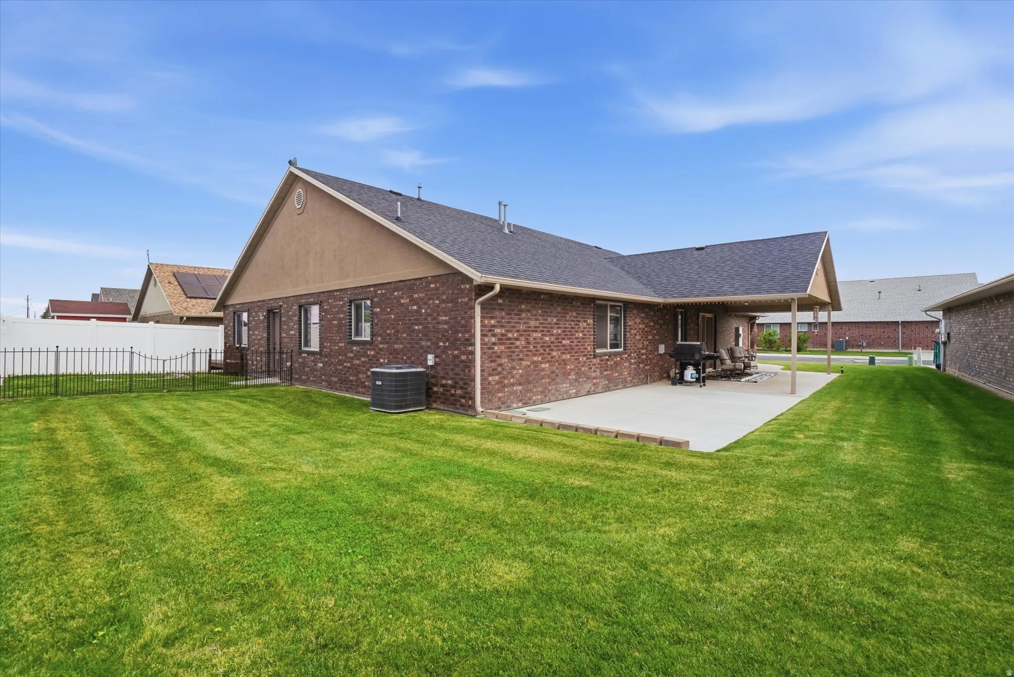 Rear view of house featuring a fenced backyard, brick siding, a shingled roof, and a patio area