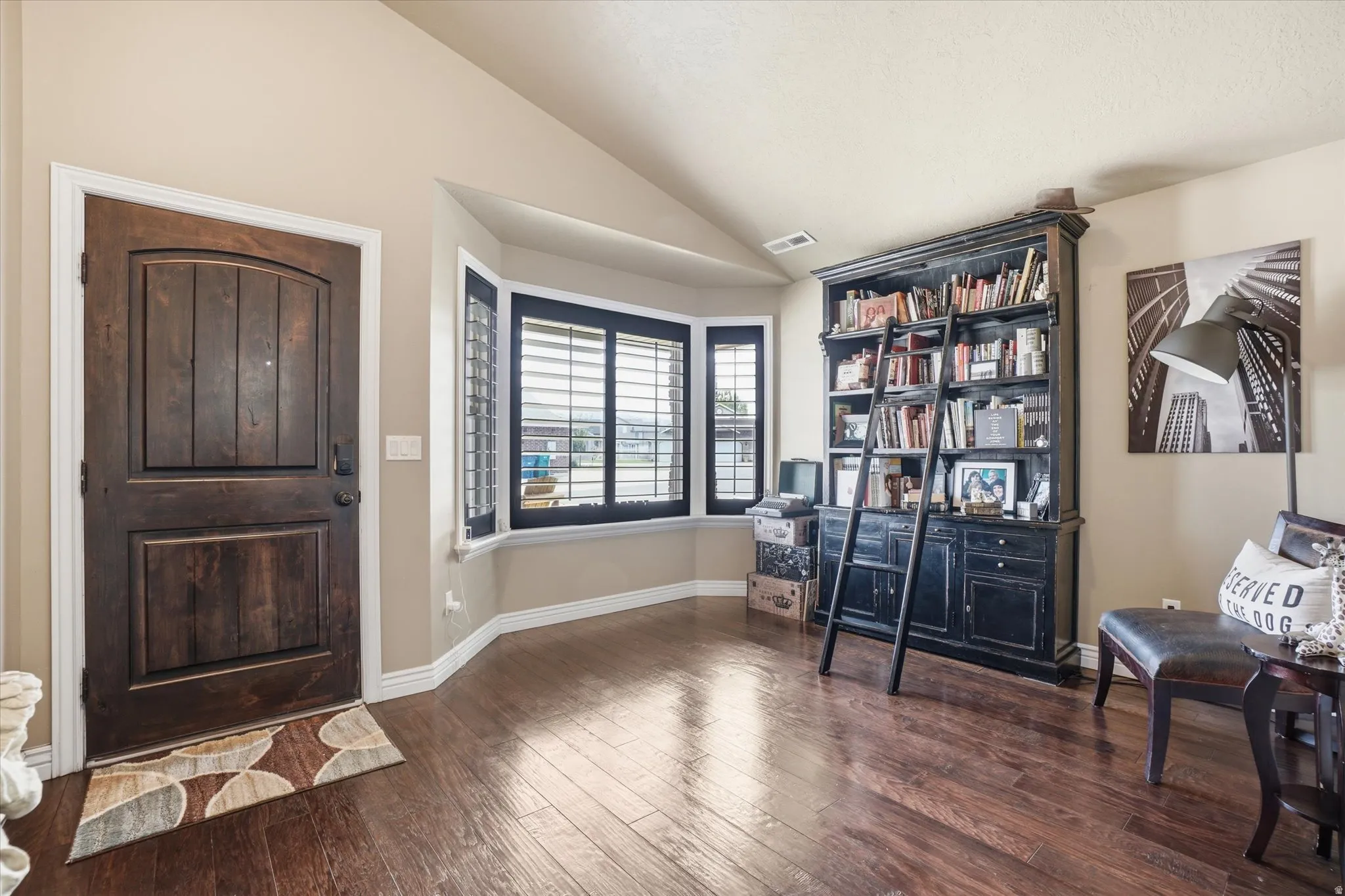 Foyer entrance featuring vaulted ceiling and dark wood-style flooring