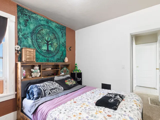 Bedroom featuring a window, wood-finish flooring, and a white paneled door