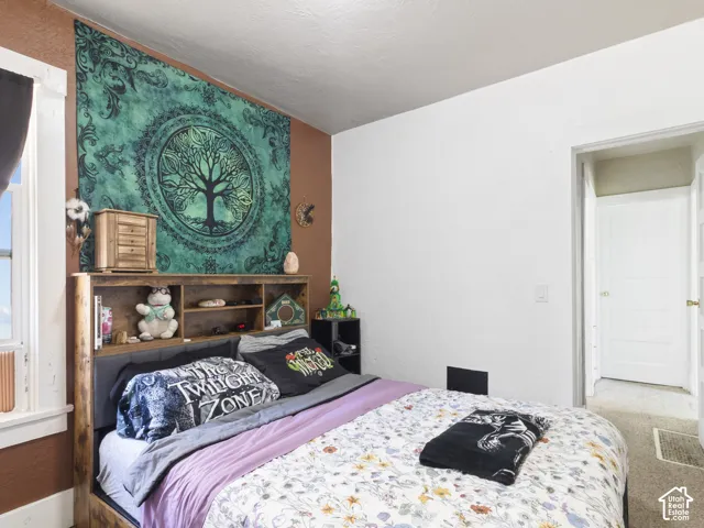 Bedroom featuring a window, wood-finish flooring, and a white paneled door
