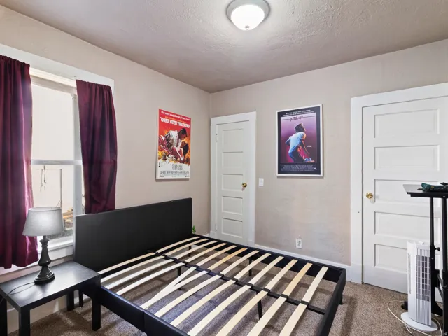 Bedroom featuring neutral wall paint, carpet flooring, a window with trim, a flush mount ceiling light fixture, and two white panel doors