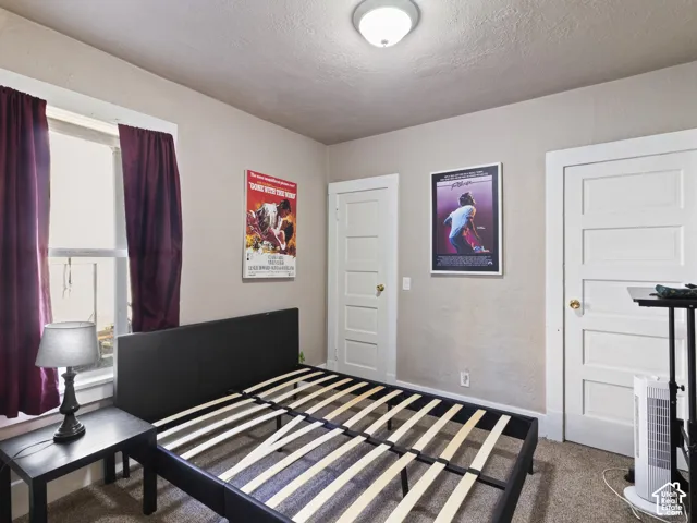 Bedroom featuring neutral wall paint, carpet flooring, a window with trim, a flush mount ceiling light fixture, and two white panel doors