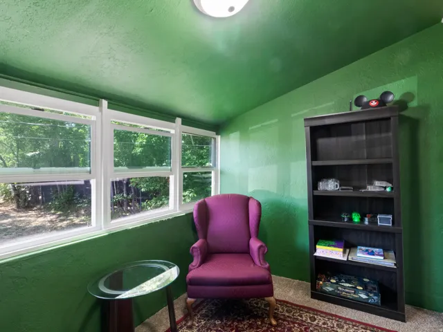 Sunroom featuring multiple windows, green textured walls, recessed ceiling lighting, and wood-finish shelving