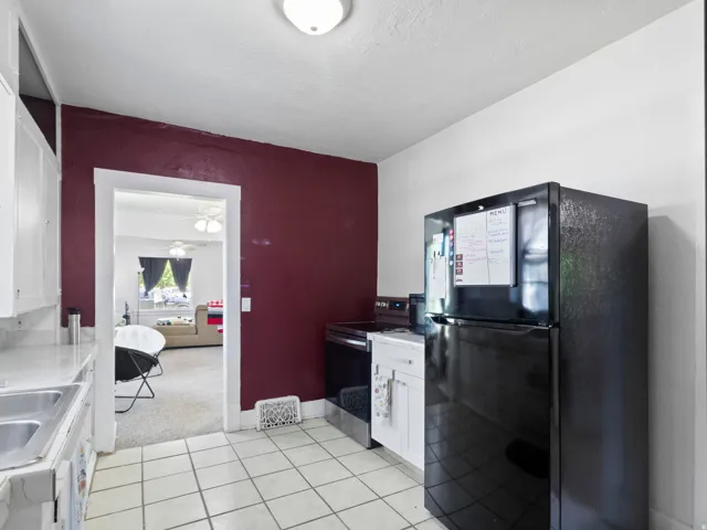 Kitchen featuring tile flooring, white cabinetry, a double basin sink, and a black refrigerator