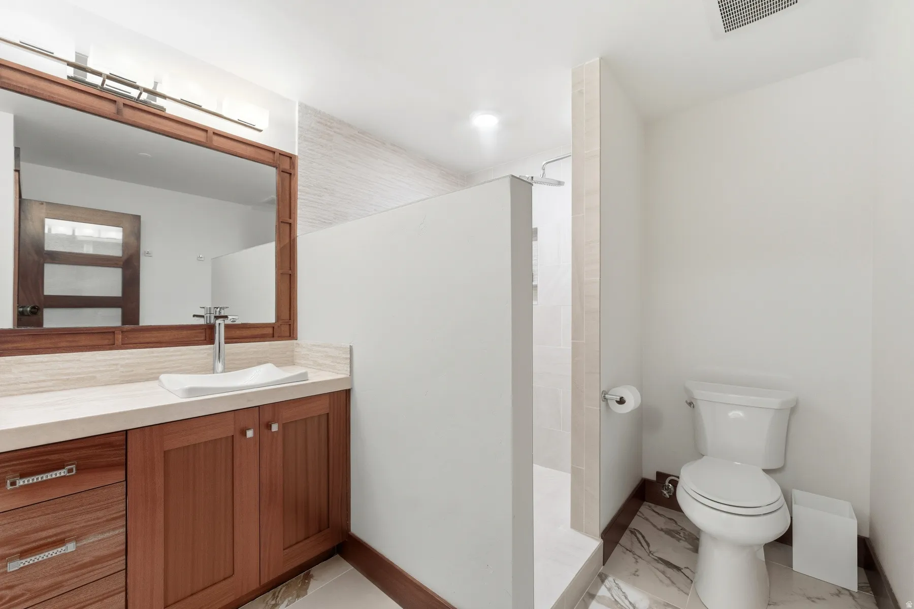 Bathroom with vanity, walk in shower, and light marble finish flooring