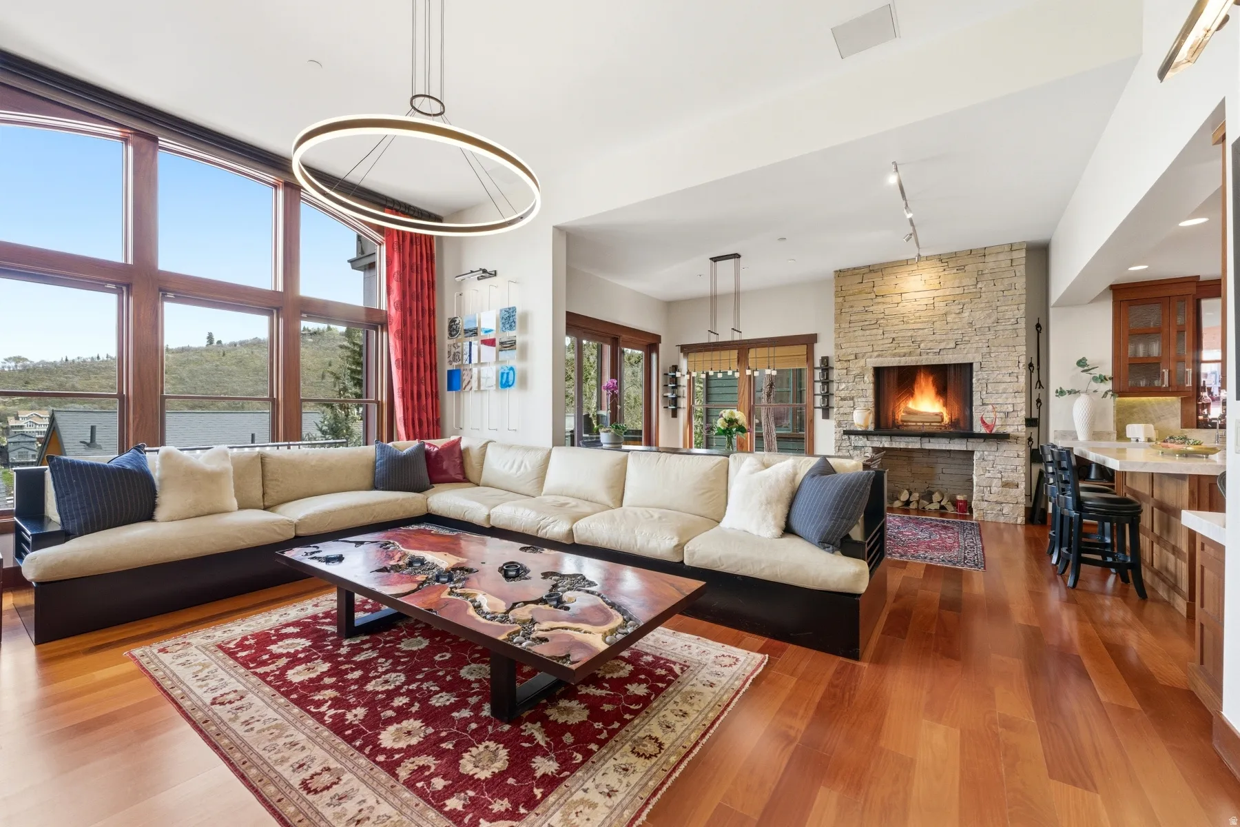 Living room featuring wood finished floors, rail lighting, and a stone fireplace