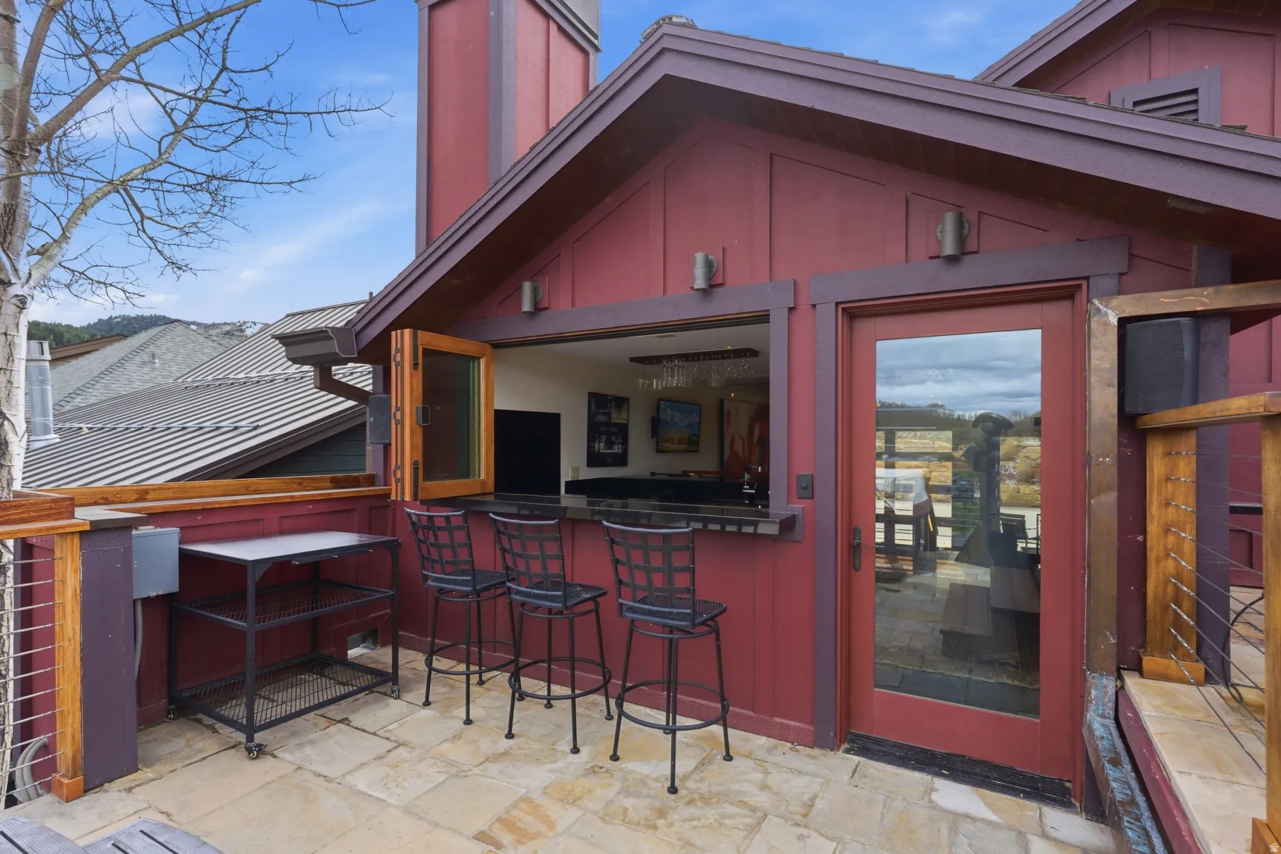 Property entrance featuring a standing seam roof, a chimney, and a patio