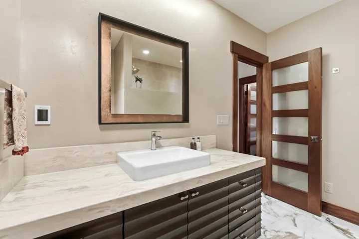 Bathroom featuring vanity, a shower, and light marble finish floors