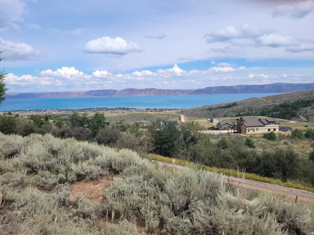 Expansive property with a multi-level residence, surrounded by natural landscaping, and featuring distant water and mountain scenery