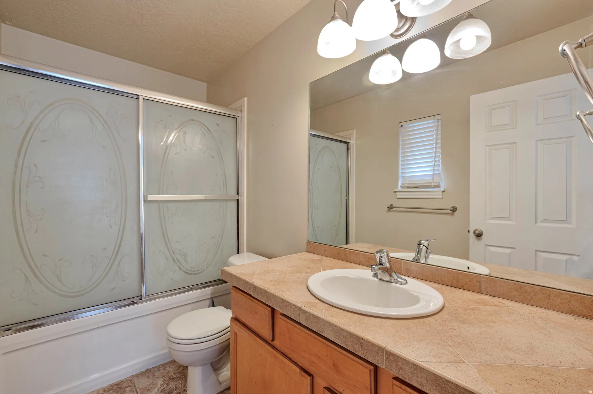 Full bathroom featuring vanity, shower / bath combination with glass door, and a textured ceiling