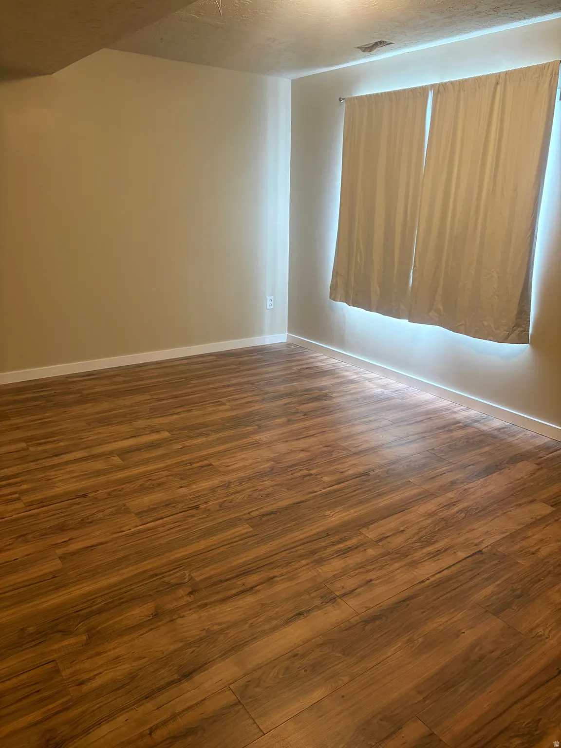 Empty room featuring dark wood-style floors and a textured ceiling