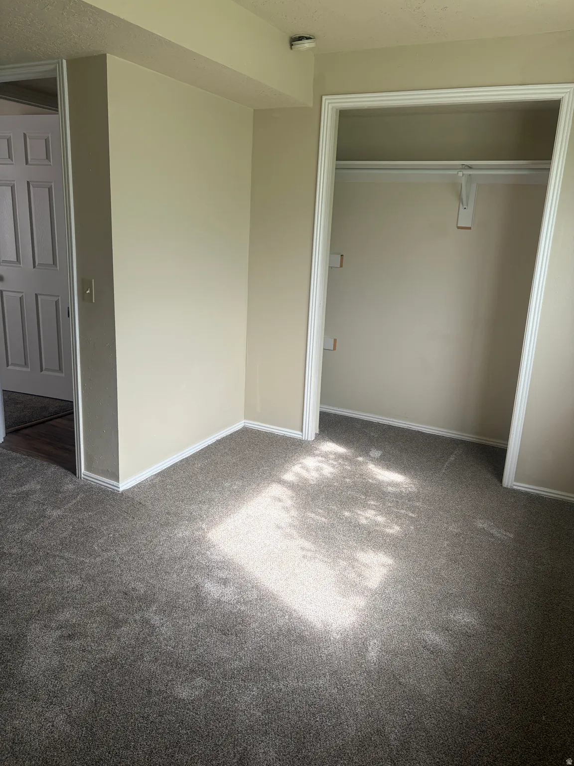 Unfurnished bedroom with dark carpet, a closet, and a textured ceiling