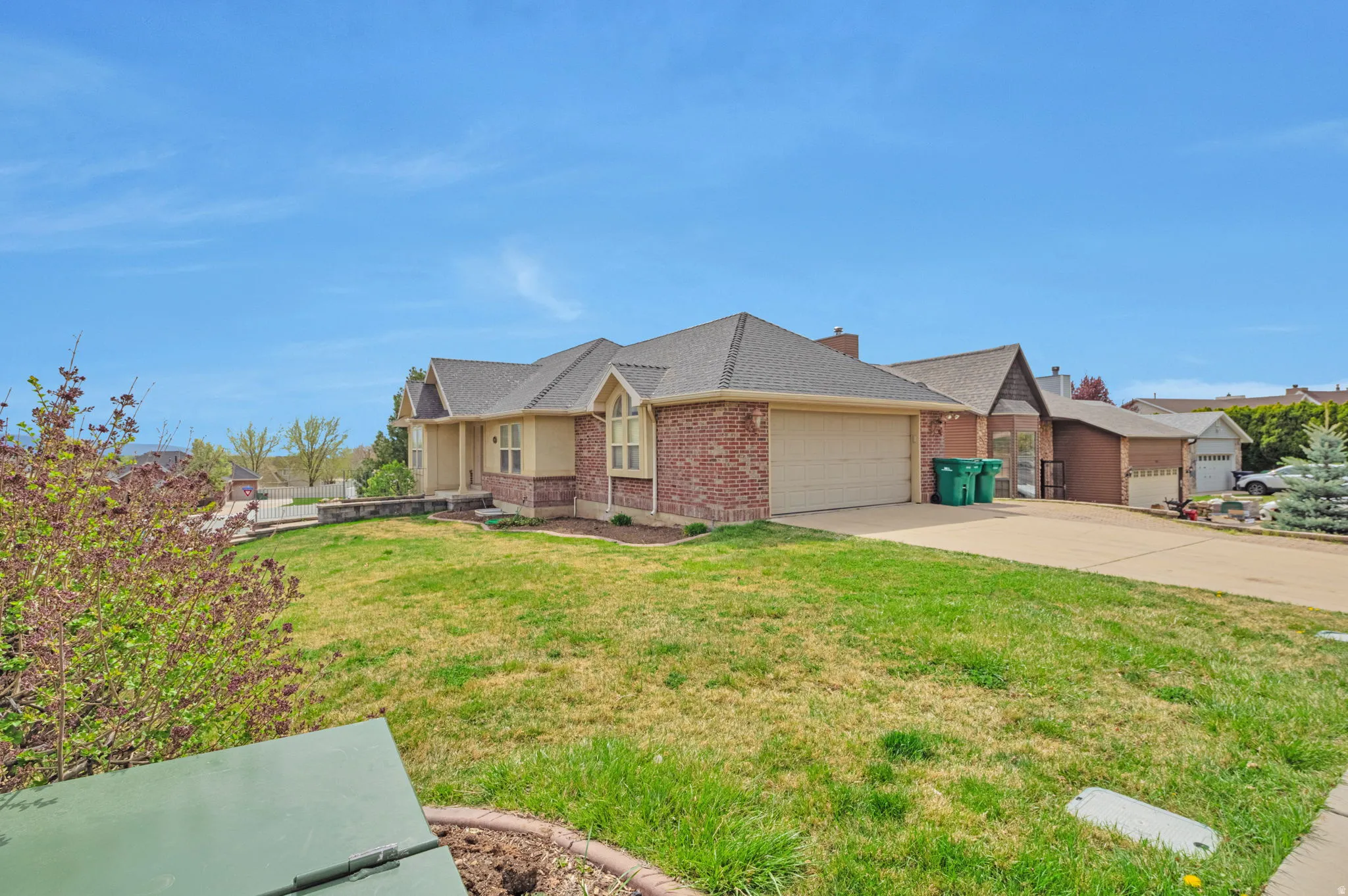 Ranch-style home featuring a garage, a front lawn, driveway, a shingled roof, and brick siding