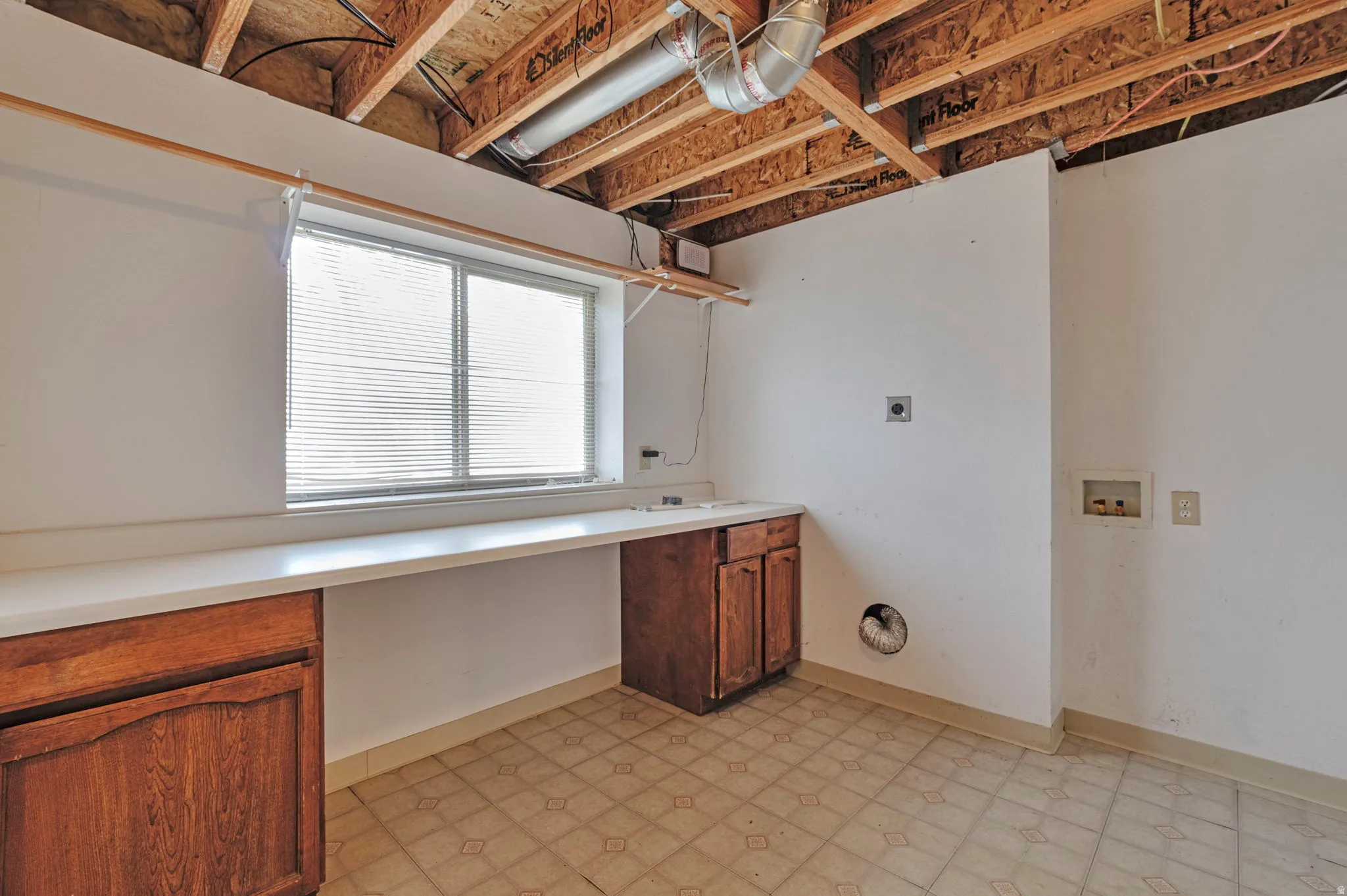 Laundry area with light floors, hookup for a washing machine, an office area, and cabinet space