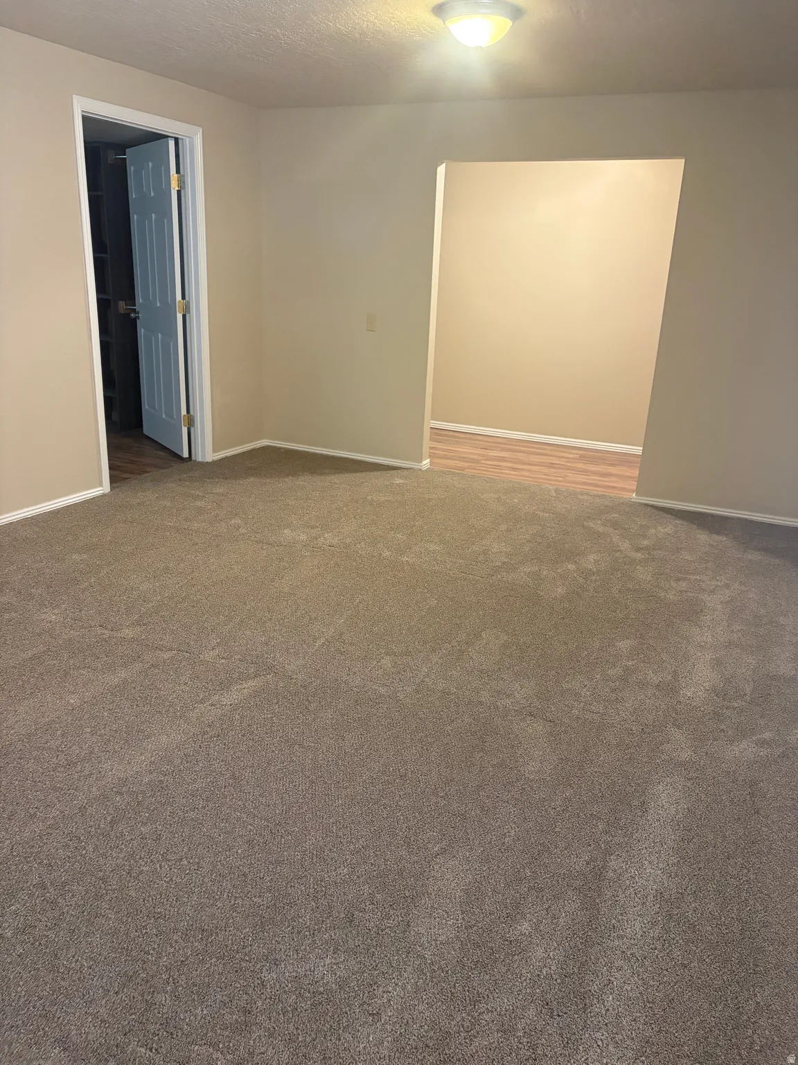 Unfurnished room featuring dark colored carpet and a textured ceiling