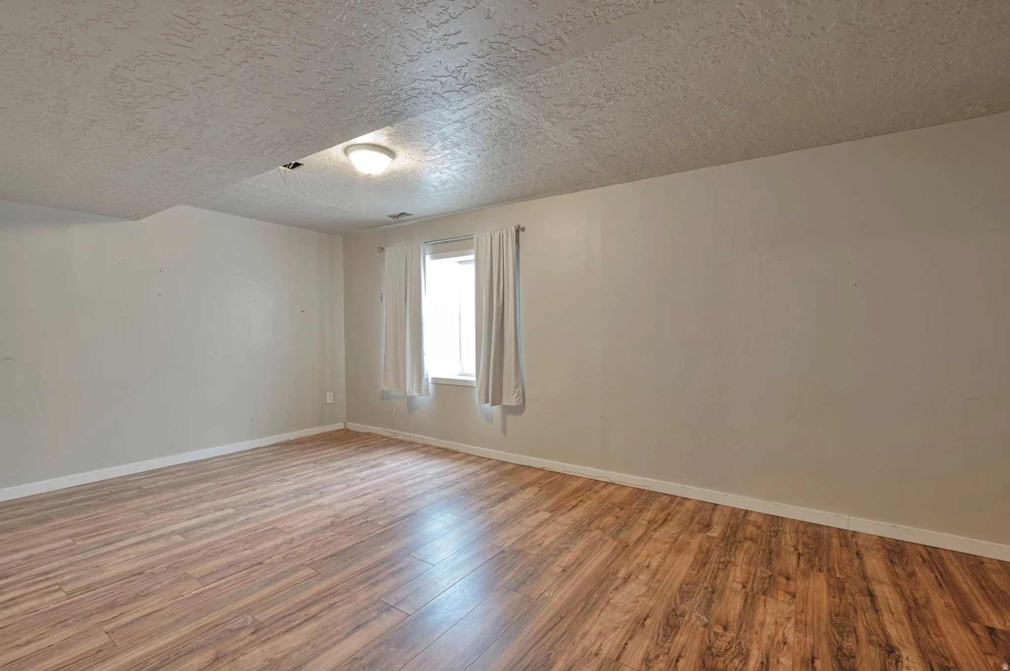 Spare room featuring a textured ceiling and wood finished floors