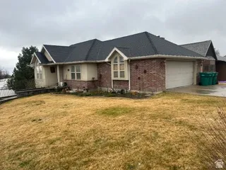 View of front of home with a front lawn, a garage, concrete driveway, and brick siding