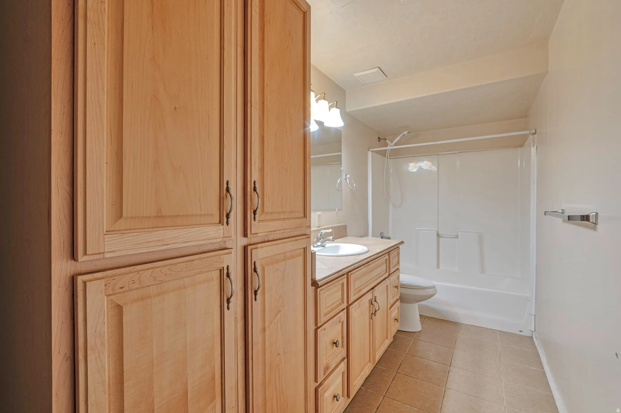 Bathroom with vanity, light tile patterned floors, and bathing tub / shower combination