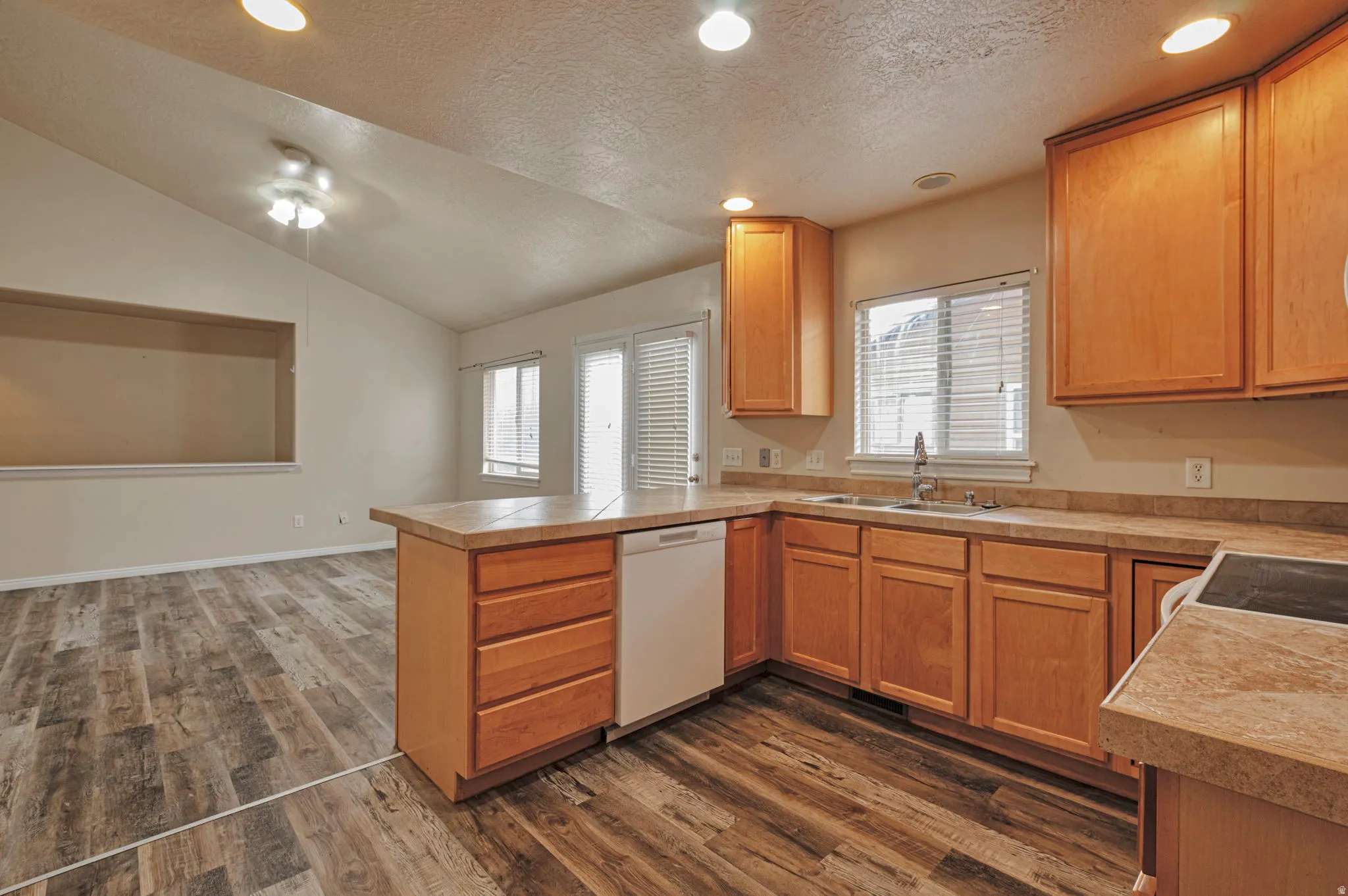 Kitchen with recessed lighting, a peninsula, light countertops, plenty of natural light, and dark wood-type flooring