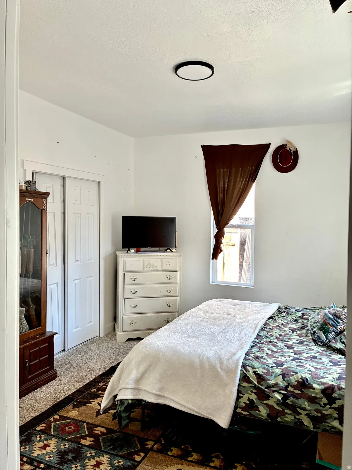 Bedroom with carpet, a textured ceiling, and a closet