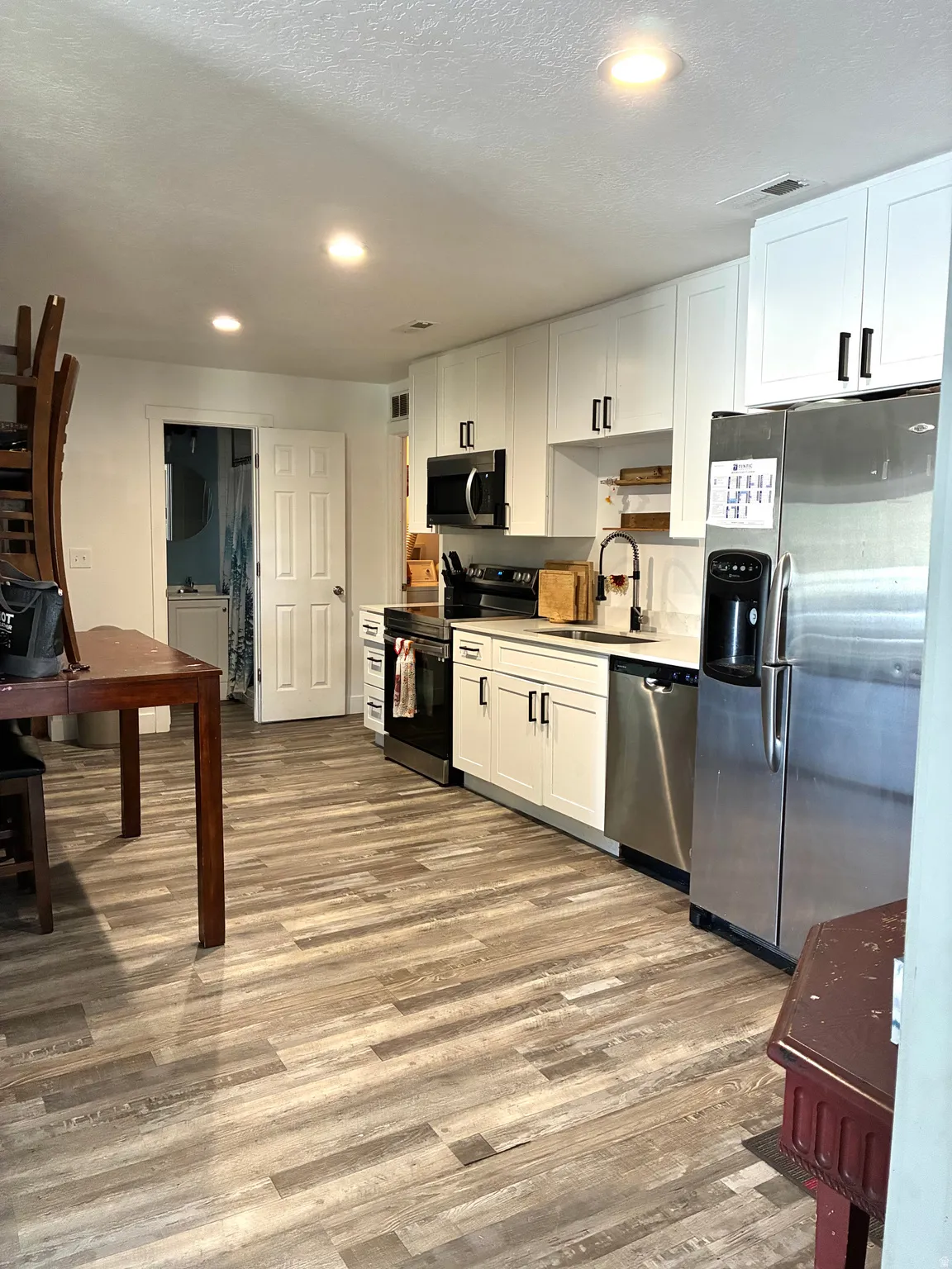 Kitchen with stainless steel appliances, white cabinetry, light wood finished floors, light countertops, and recessed lighting