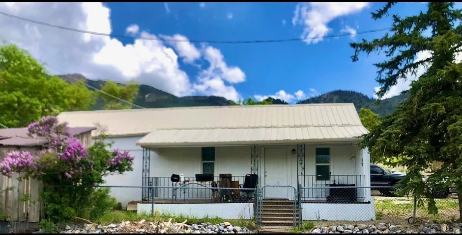 View of front of property featuring a porch, stucco siding, a mountain view, and a metal roof