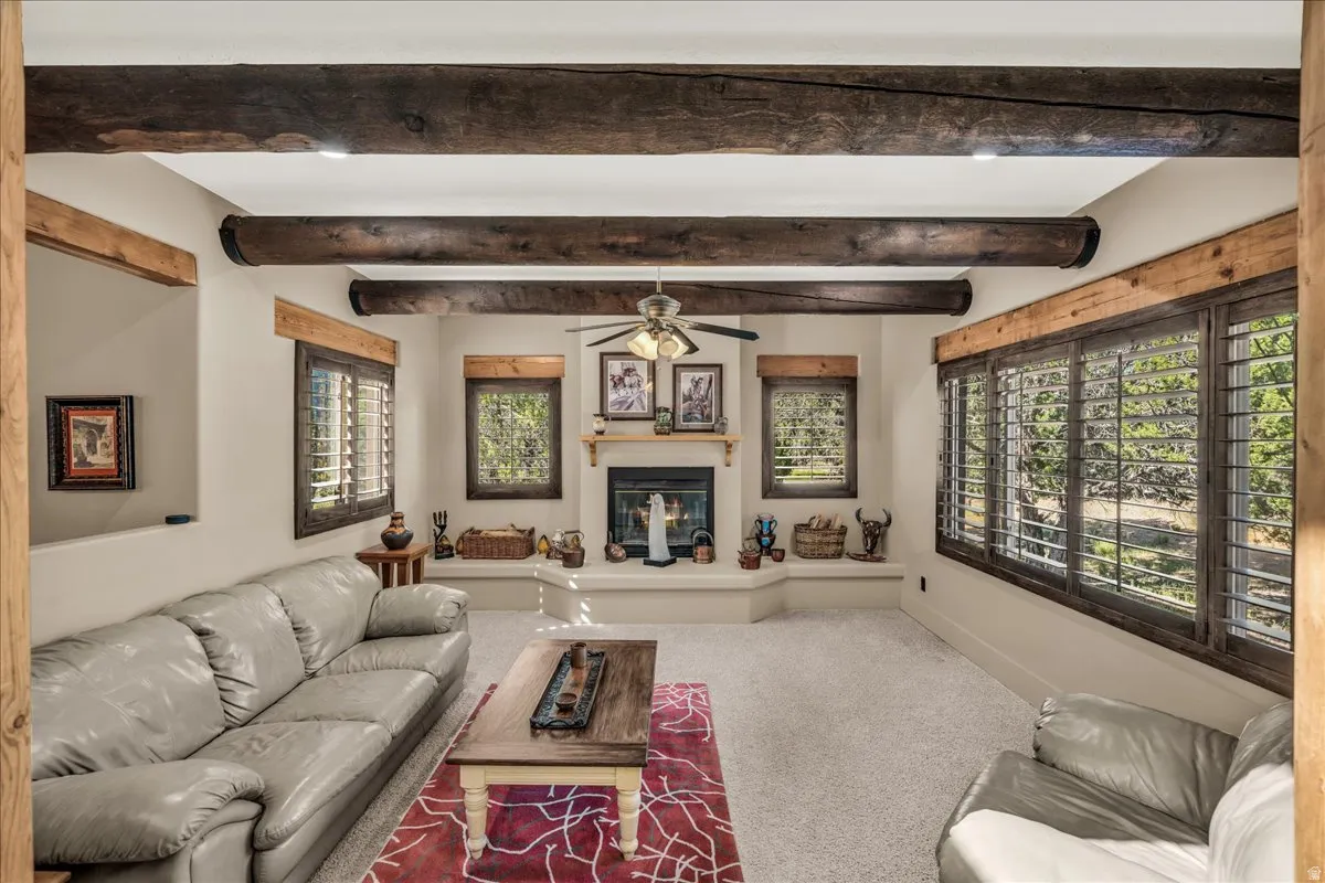 Carpeted living room with a glass covered fireplace and baseboards