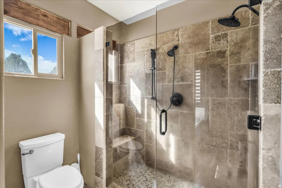 Bathroom featuring toilet and a stall shower