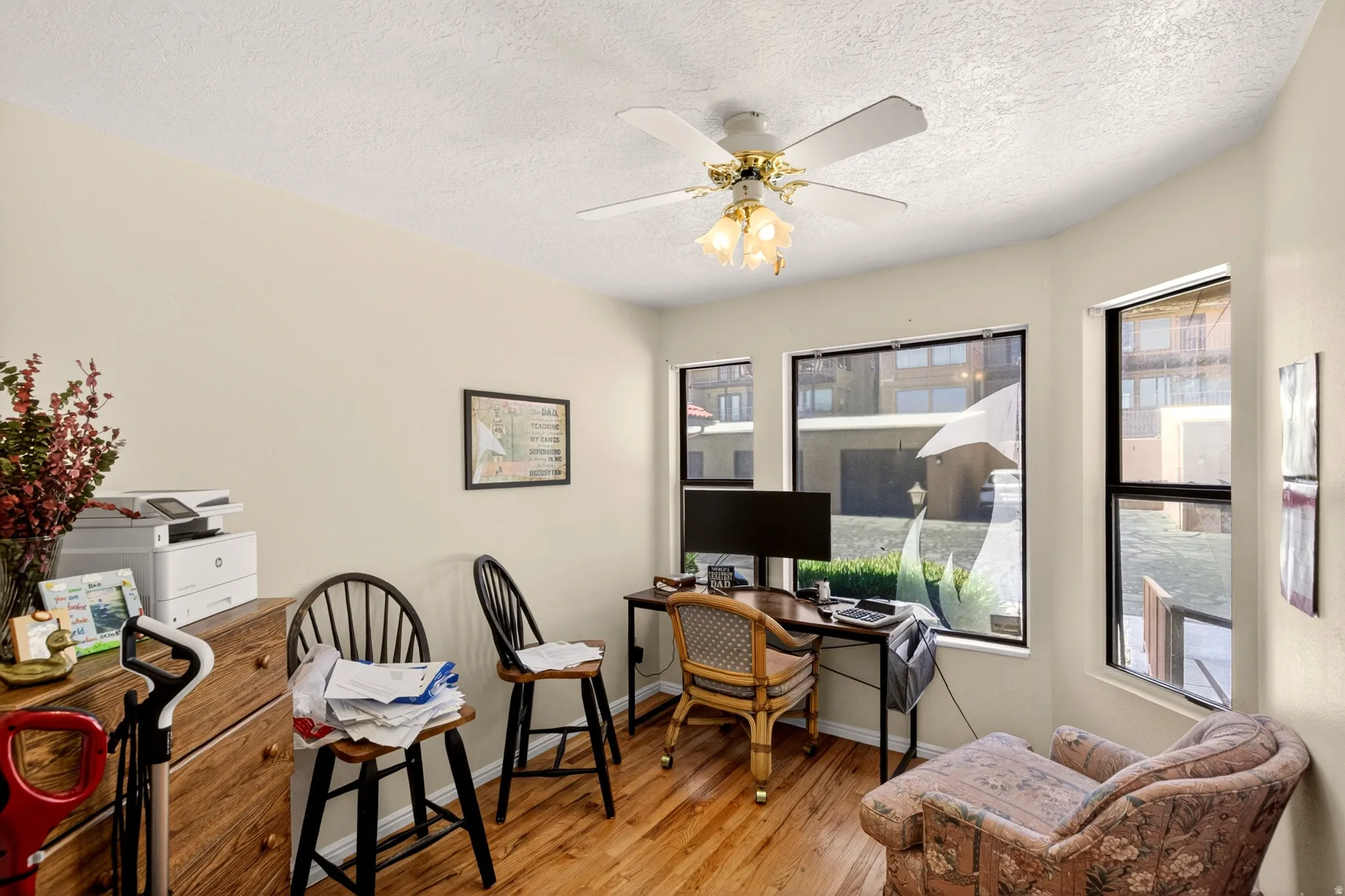 Home office featuring light wood-style flooring, a ceiling fan, and a textured ceiling