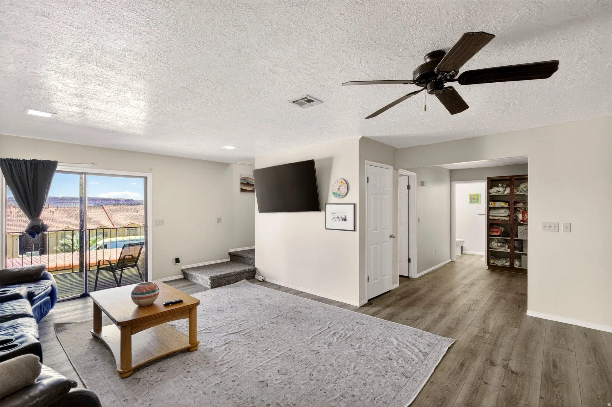 Living area with wood finished floors, a ceiling fan, and a textured ceiling