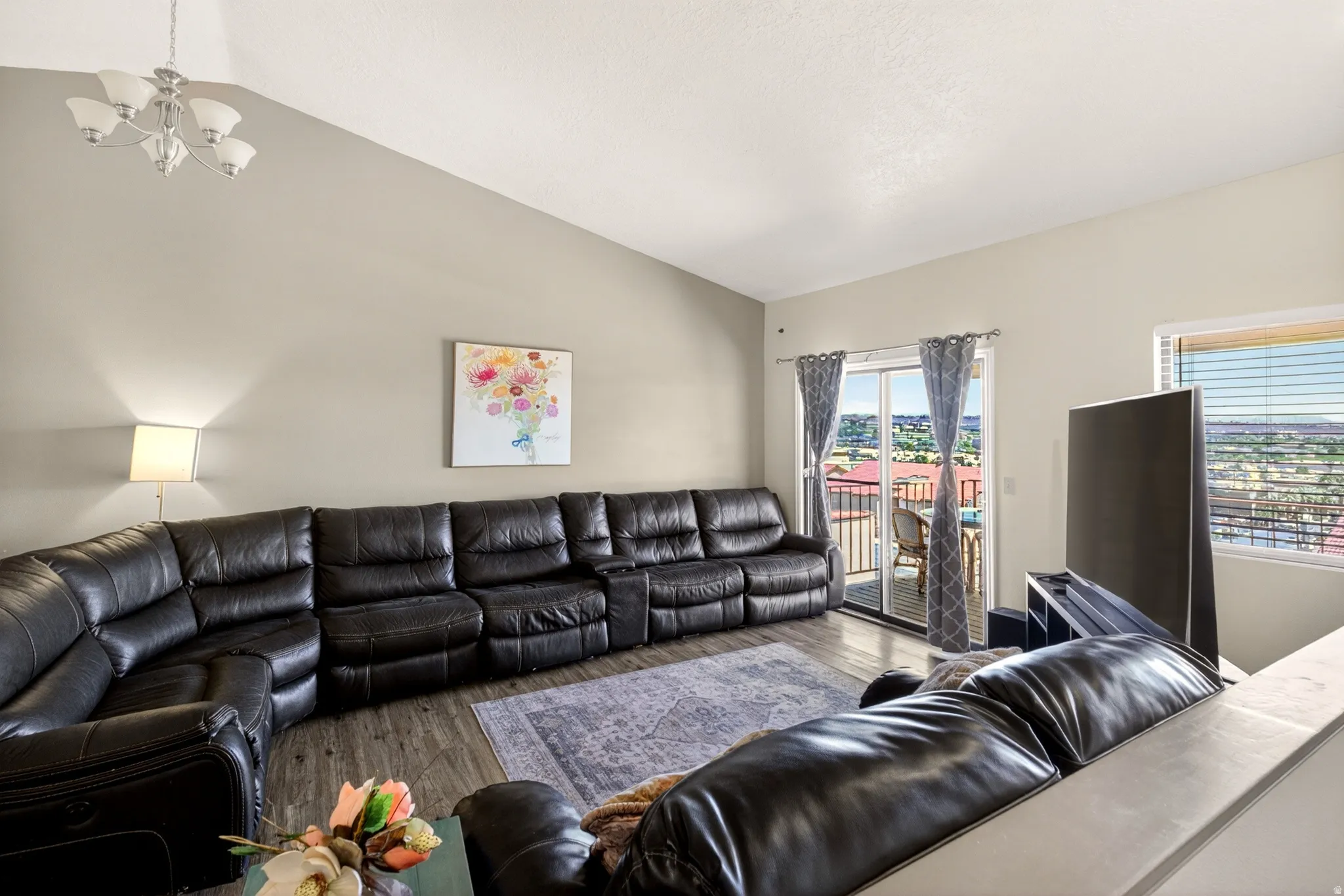 Living area with lofted ceiling, suspended lighting, and wood finished floors