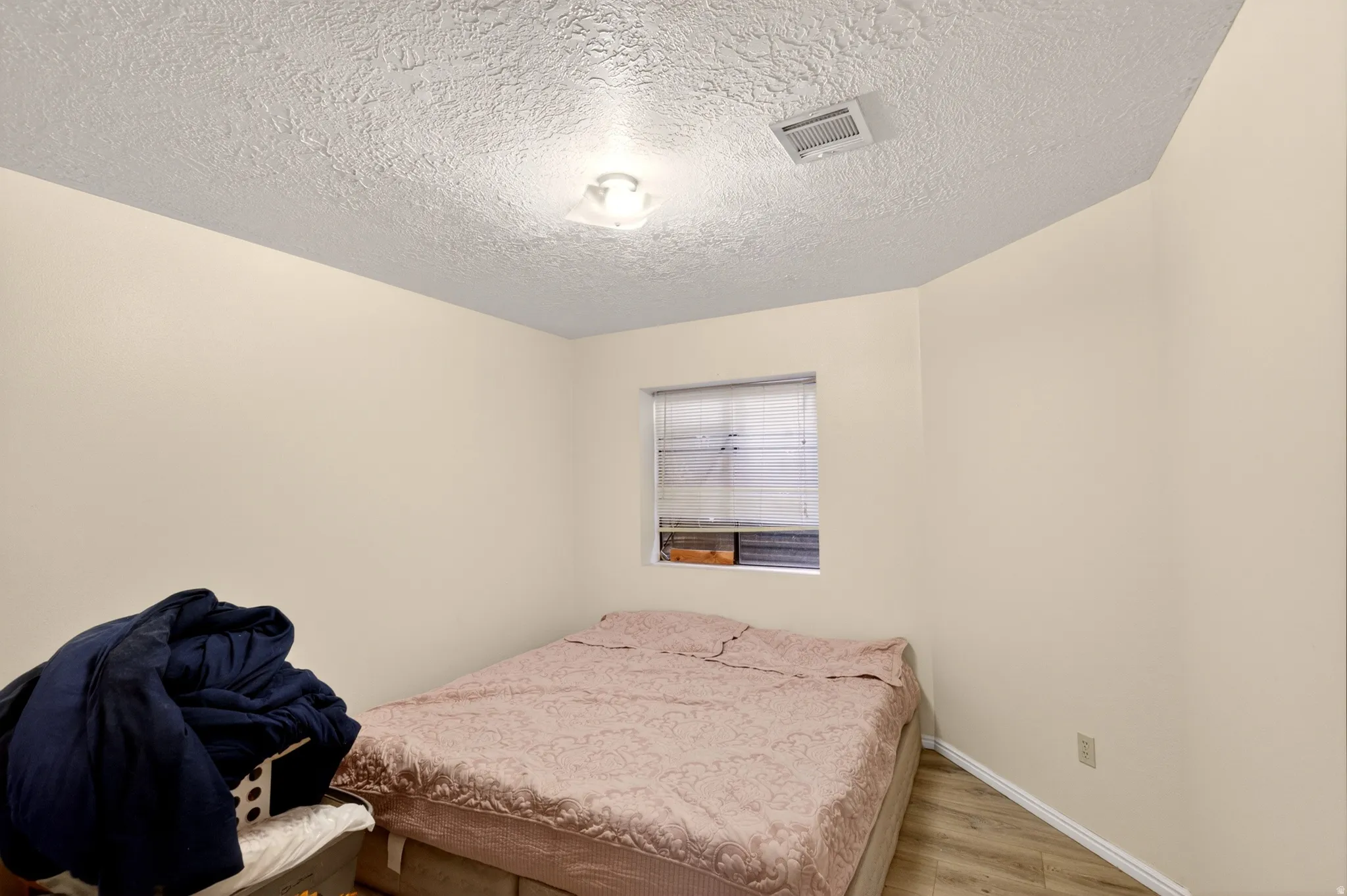 Bedroom featuring wood finished floors and a textured ceiling