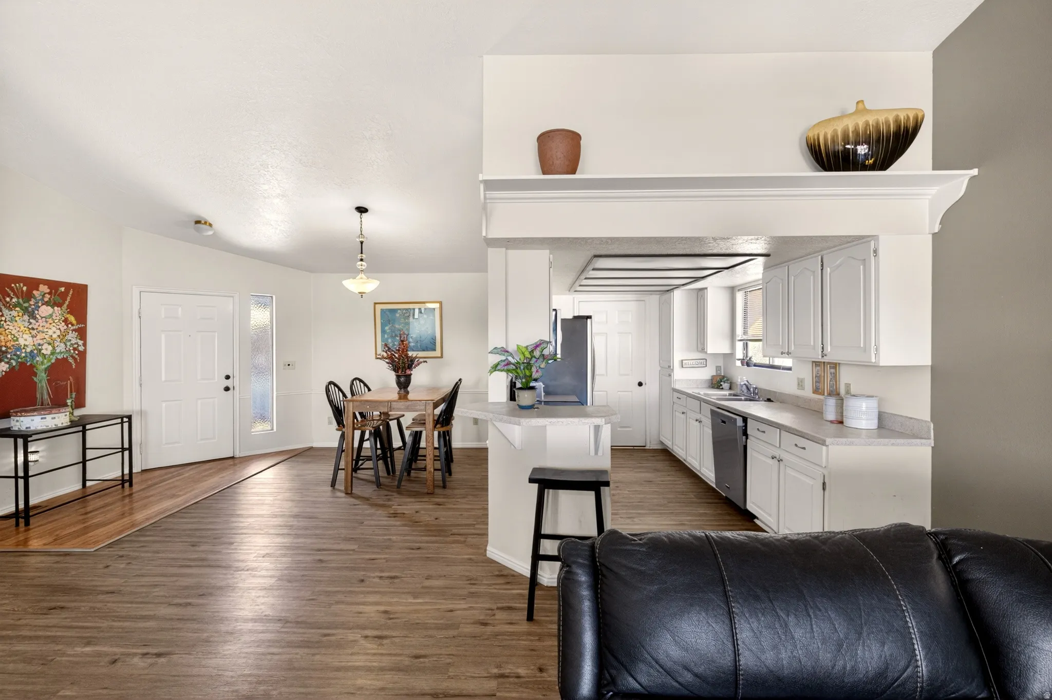 Kitchen featuring light countertops, white cabinetry, dark wood-type flooring, a kitchen breakfast bar, and stainless steel appliances