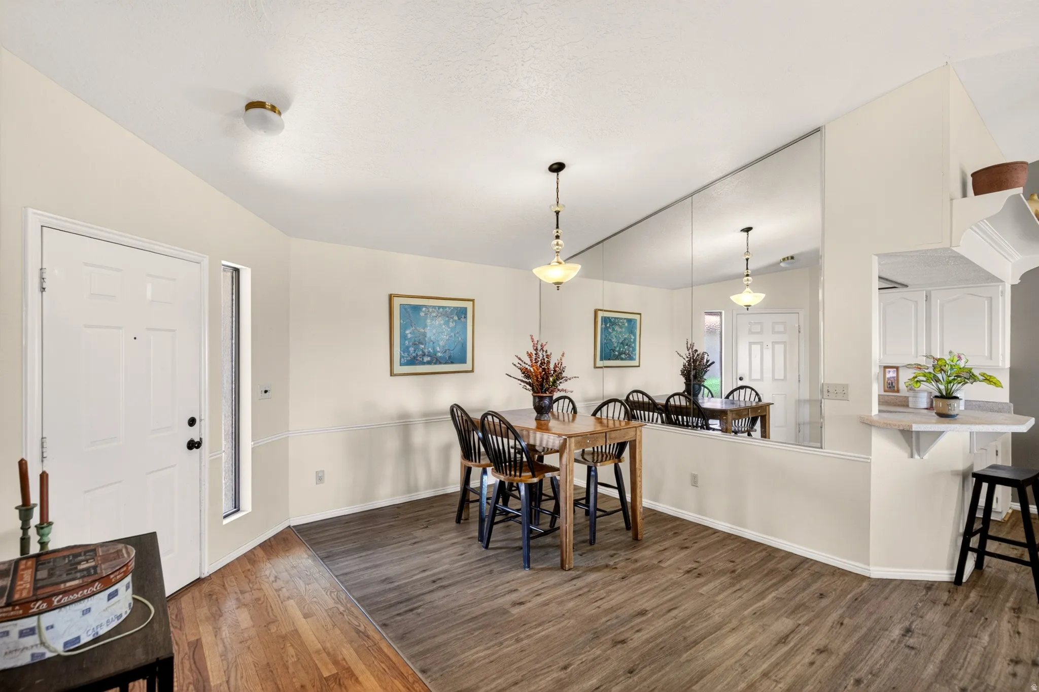 Dining space with dark wood-style flooring and vaulted ceiling