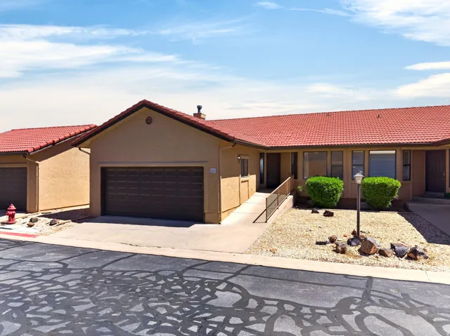 View of front of property featuring a tile roof, stucco siding, a garage, and driveway