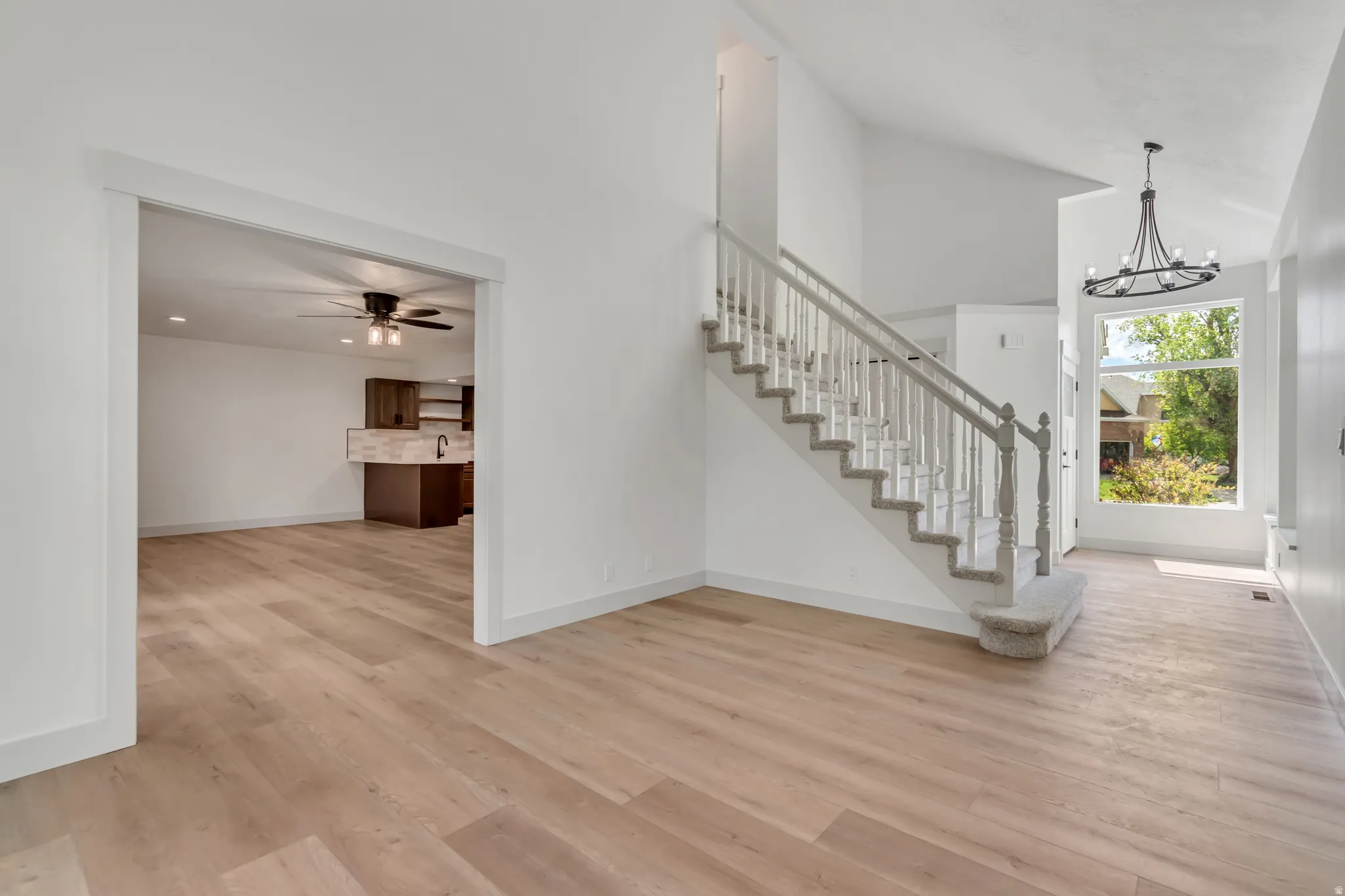 Stairway featuring a high ceiling, hanging lights, wood finished floors, and ceiling fan