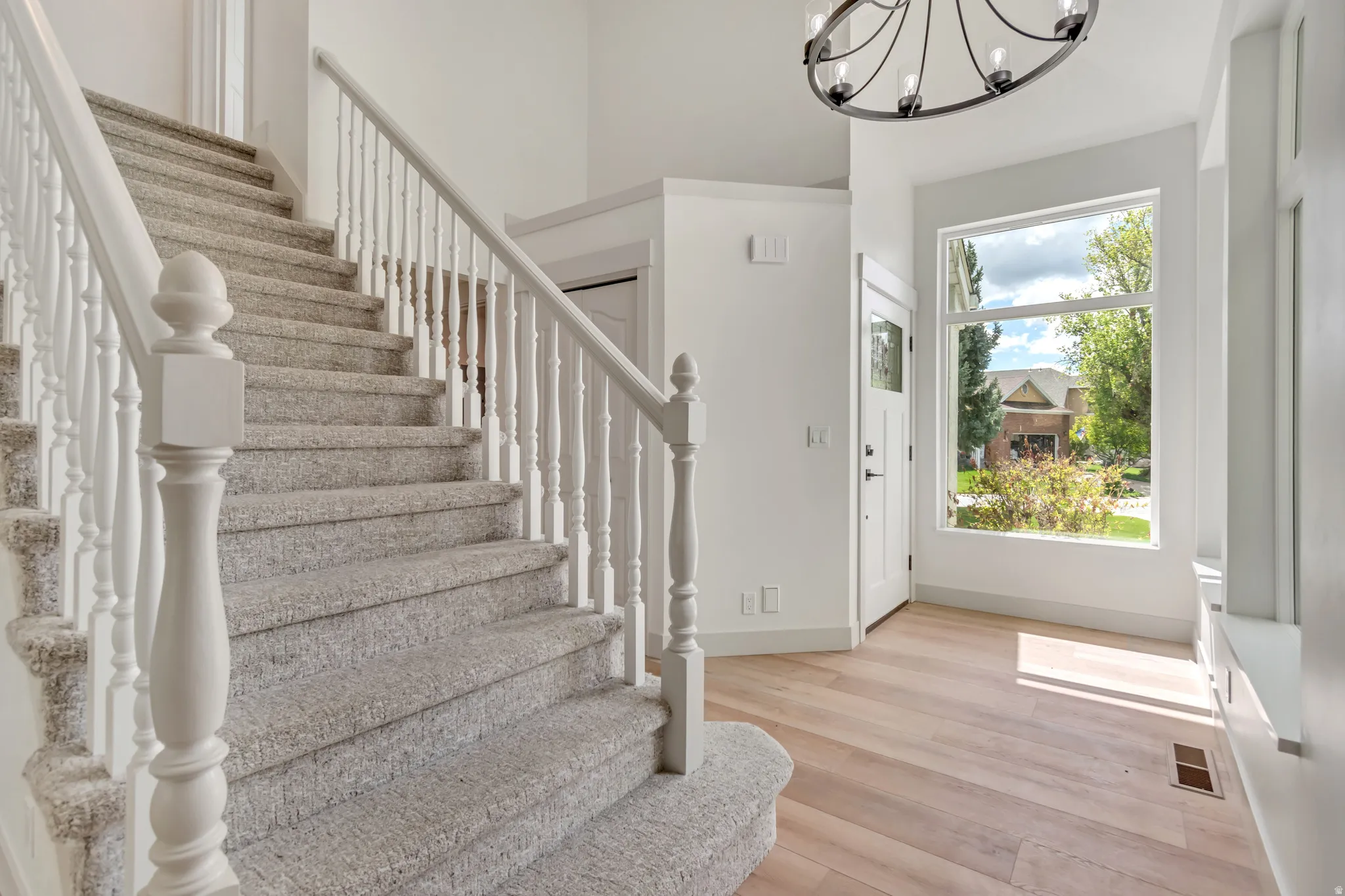 Foyer with light wood-style floors and a chandelier