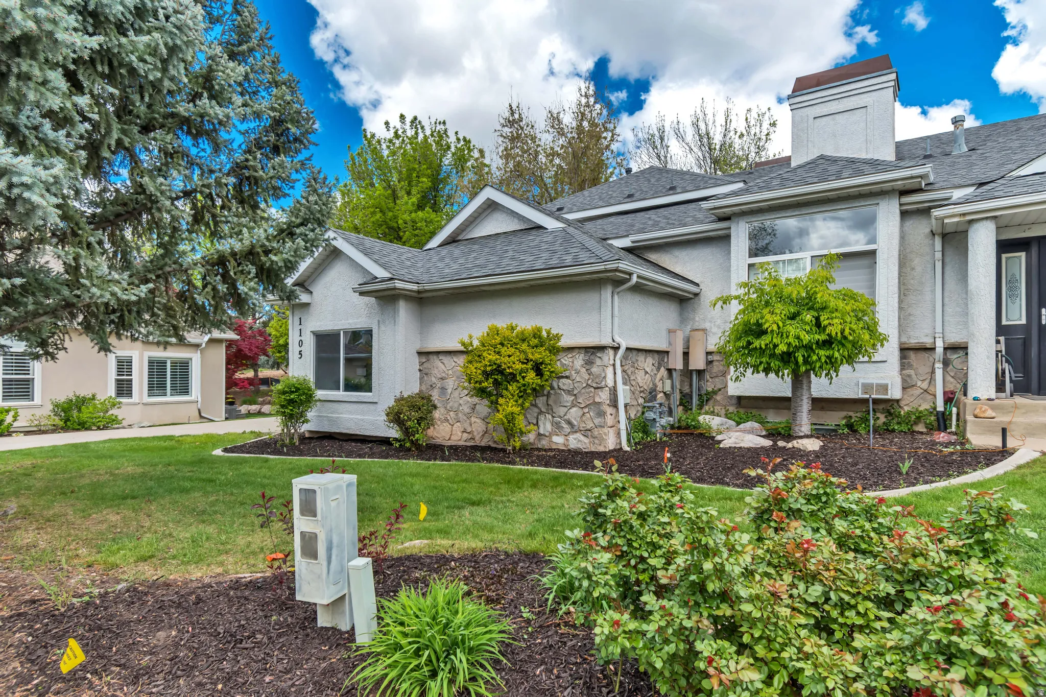 View of front of home featuring a front lawn, stucco siding, a shingled roof, and stone siding