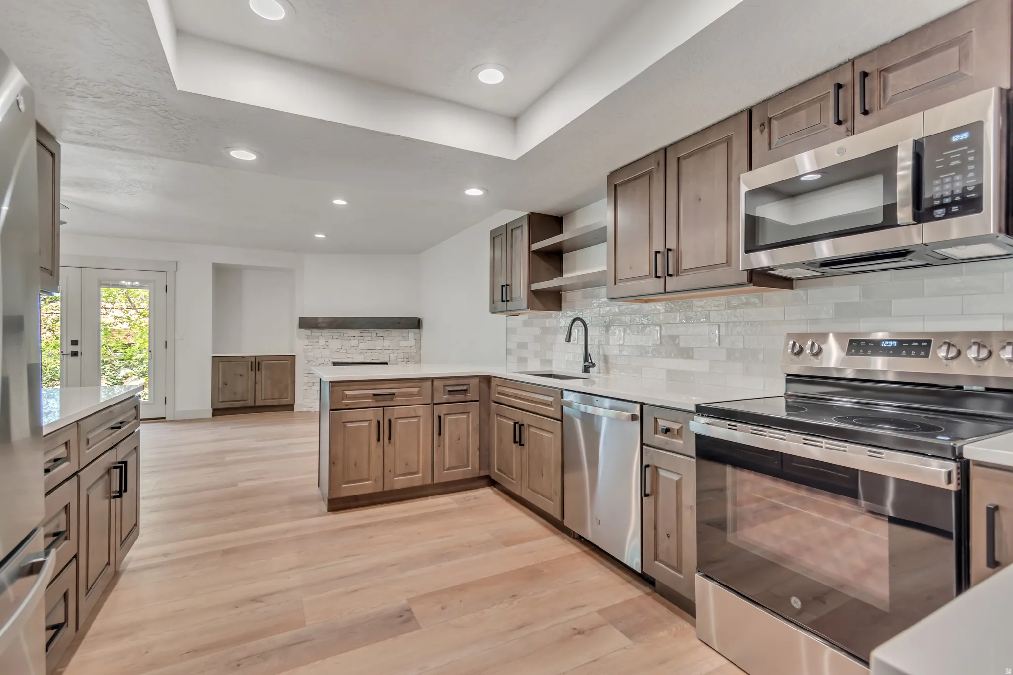 Kitchen with a peninsula, stainless steel appliances, open shelves, recessed lighting, and light wood-type flooring