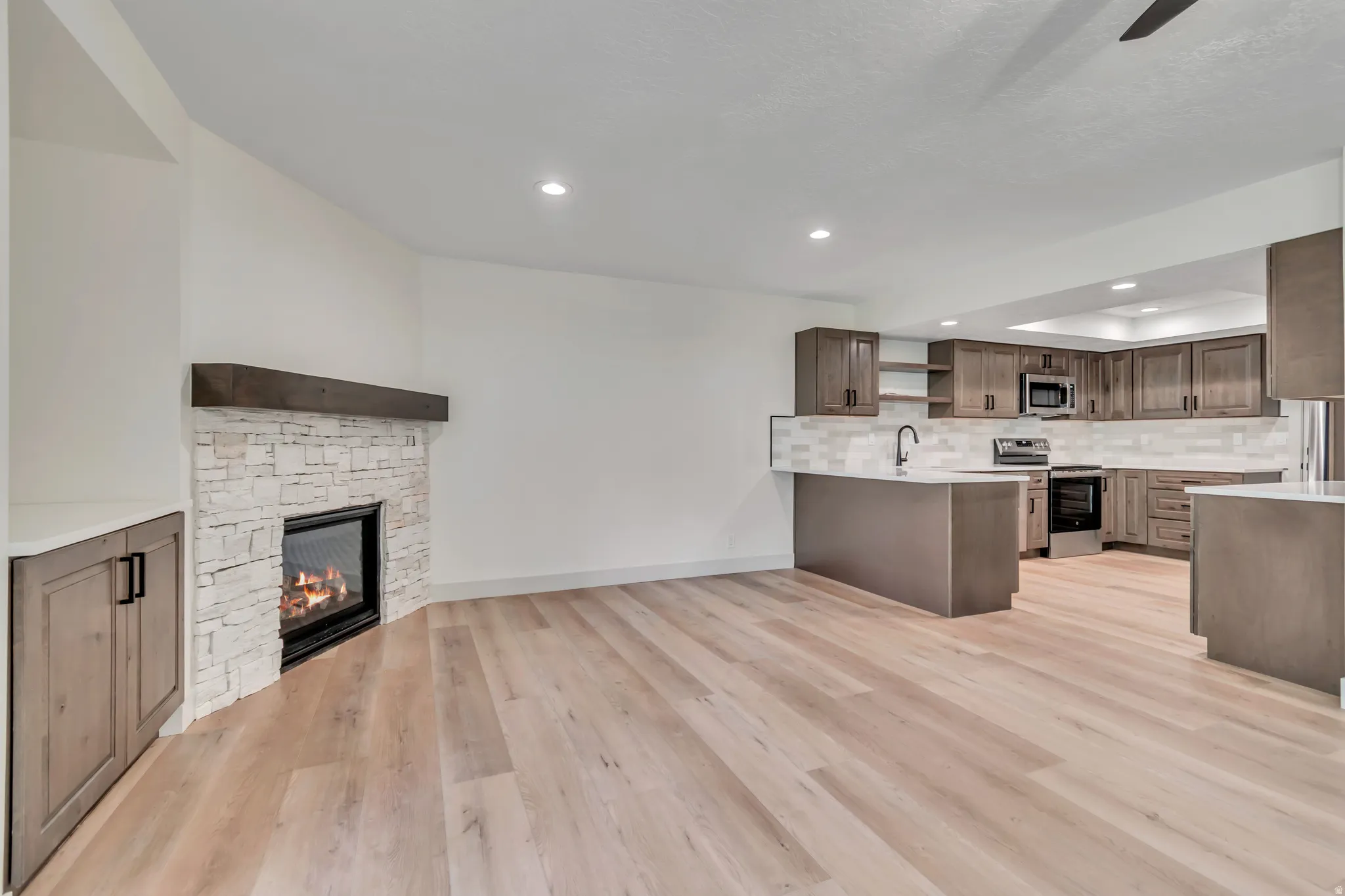 Kitchen with open shelves, open floor plan, stainless steel appliances, a fireplace, and tasteful backsplash