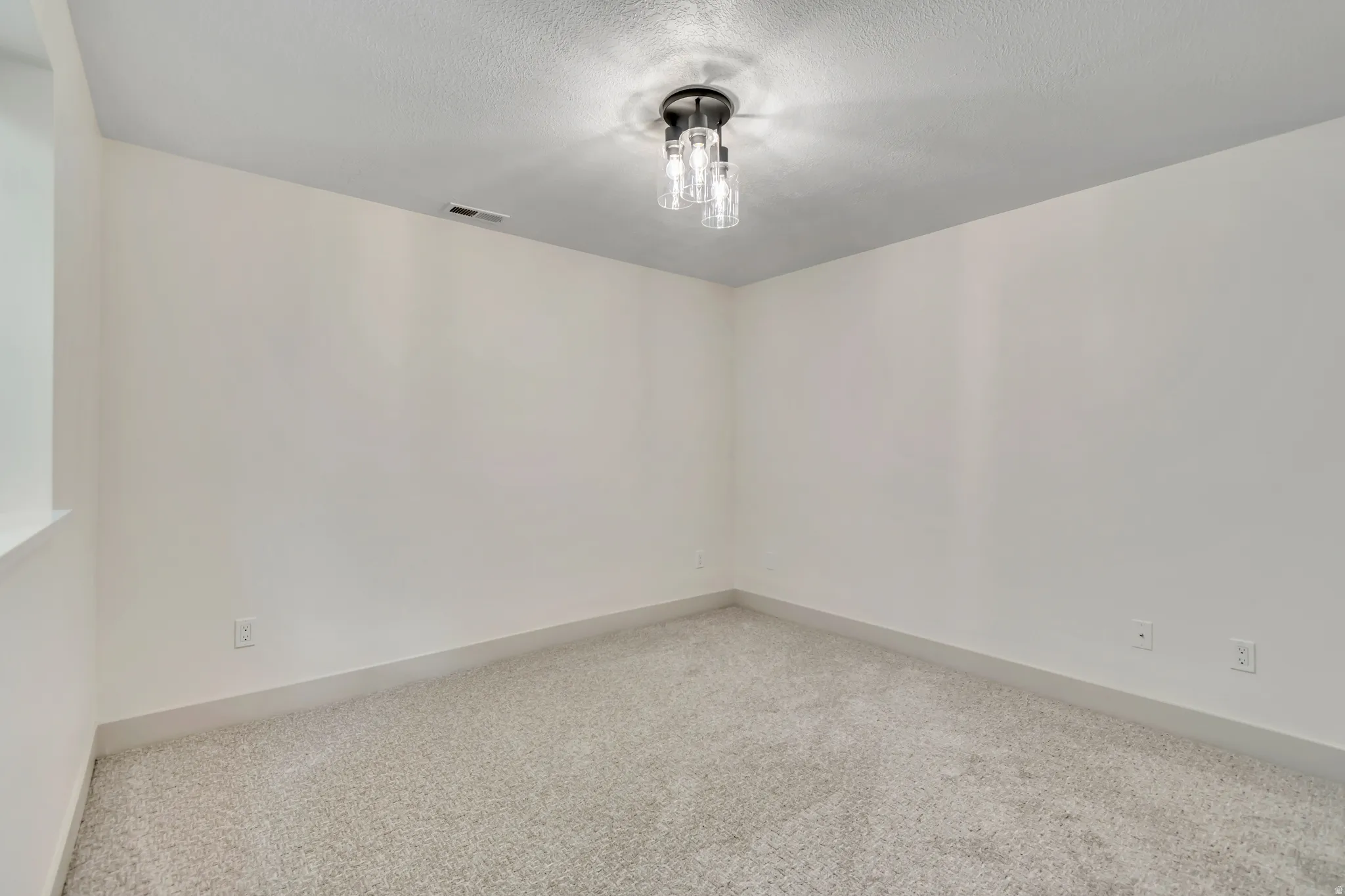 Carpeted spare room with baseboards and a textured ceiling