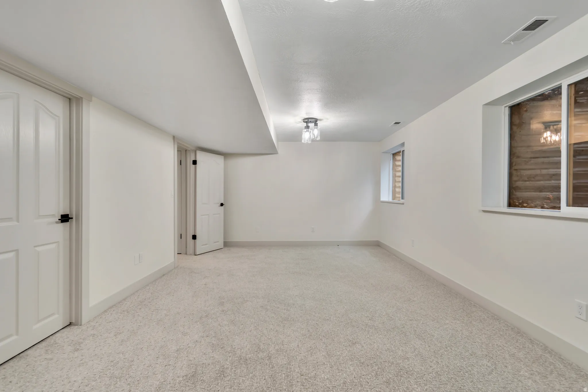 Unfurnished room featuring light carpet and baseboards